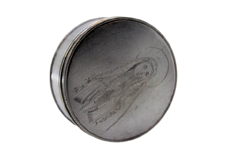 Caixa de comprimidos em prata de forma circular com imagem de Nossa Senhora de Fátima gravada na tampa amovível.